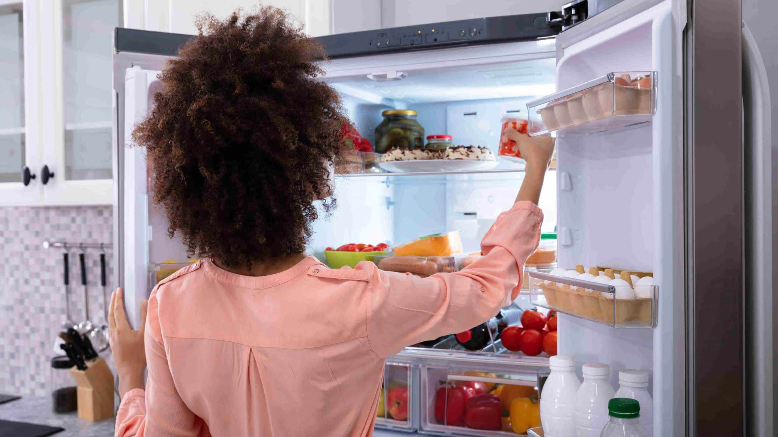 Une femme range des produits dans son réfrigérateur