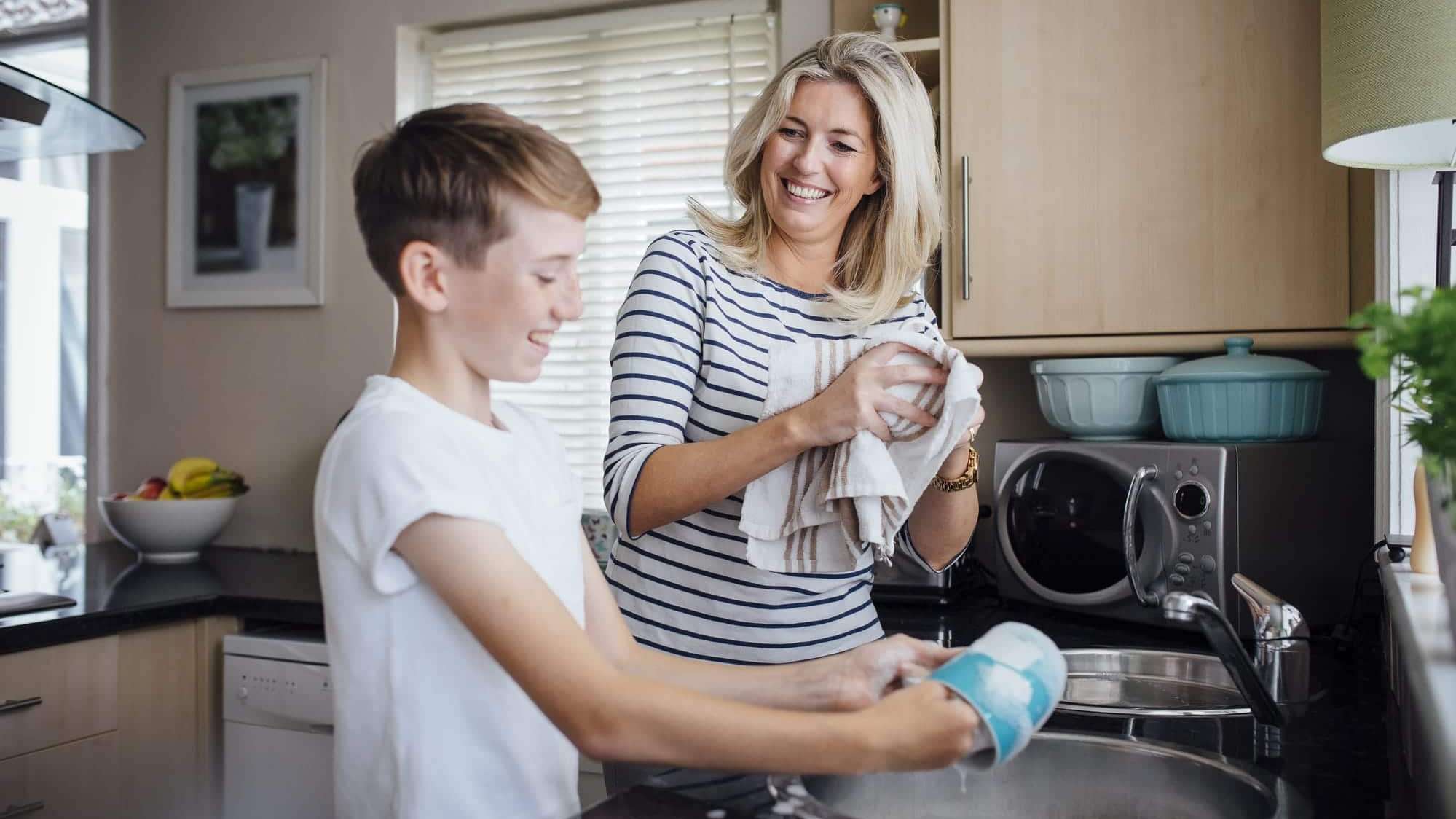 Une mère et son jeune fils font la vaisselle