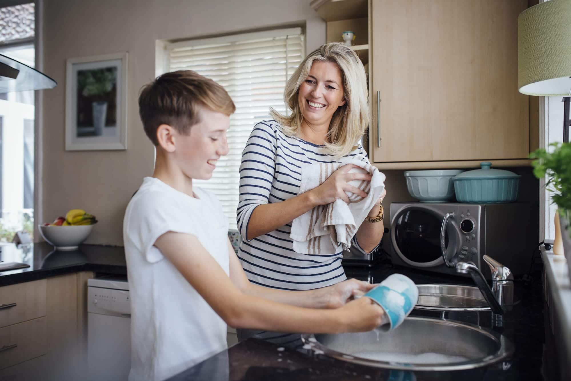 Une mère et son jeune fils font la vaisselle