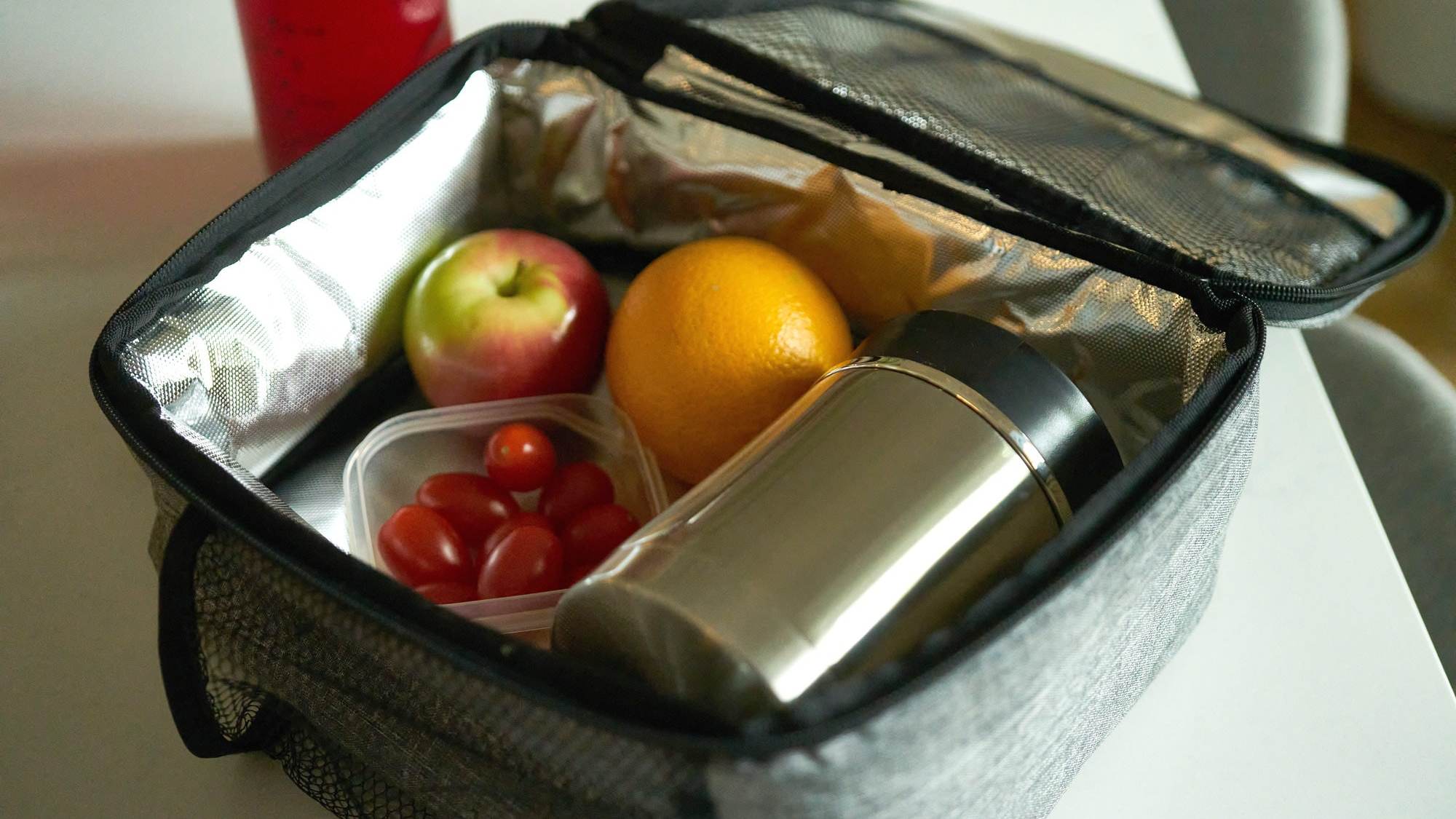 Photo d'une boîte à lunch avec un Thermos et des fruits