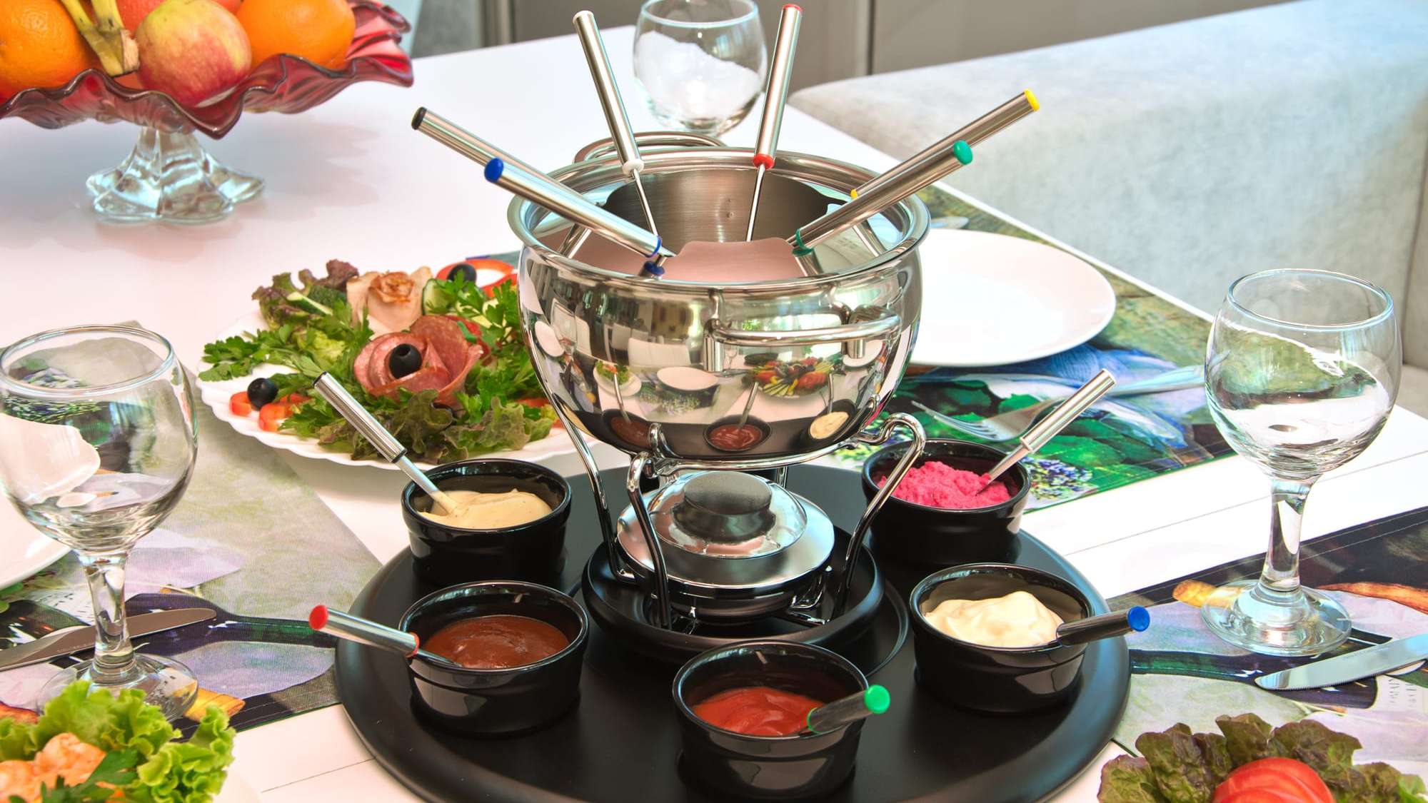 Une table dressée avec un caquelon à fondue chinoise et des sauces