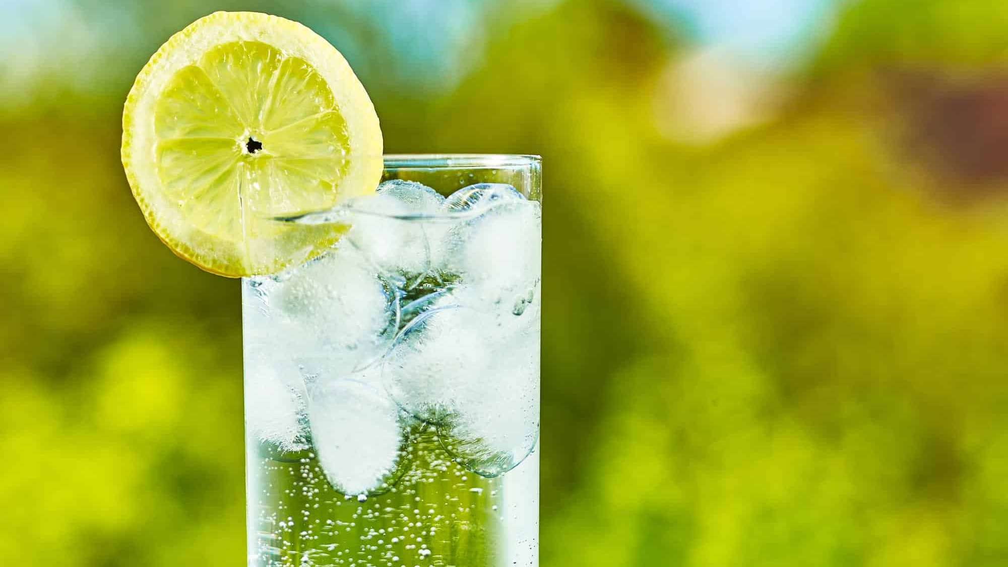 un cocktail transparent garni de lime sur un fond de nature