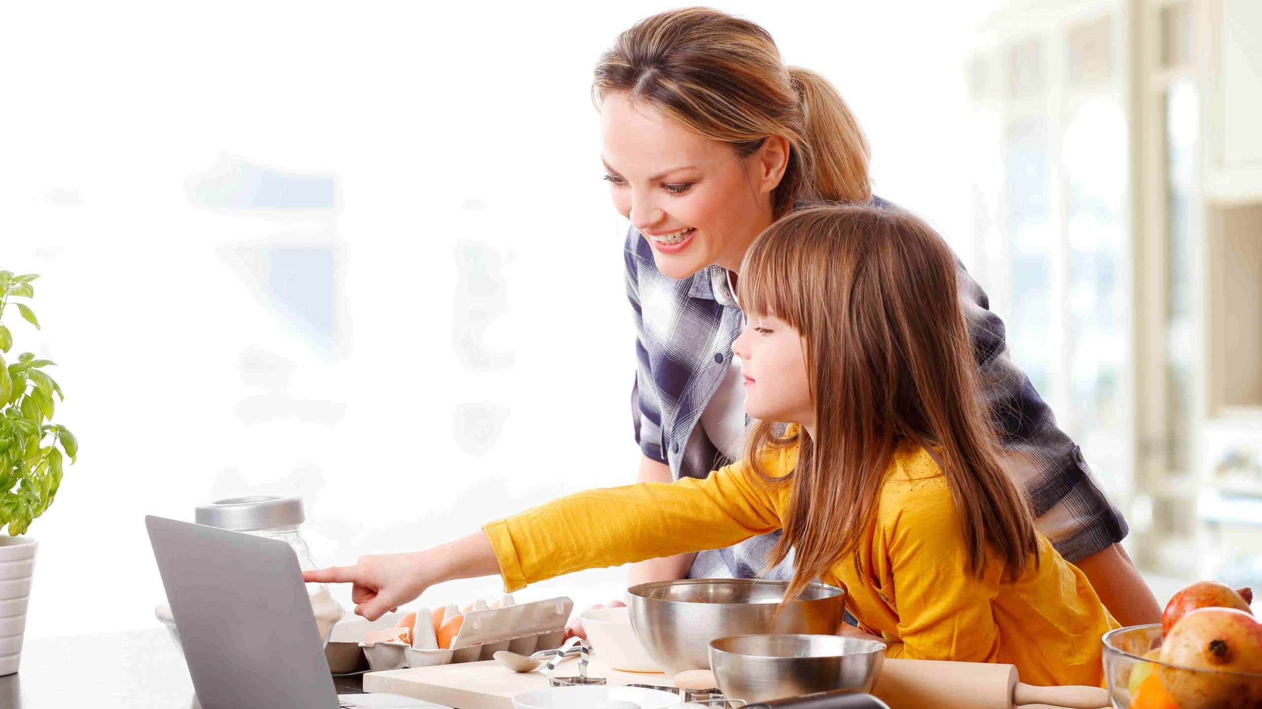 Une mère consulte un blogue culinaire en cuisinant avec sa fille.