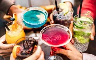 Un groupe de personne portent un toast avec des mocktails sans alcool festifs et colorés