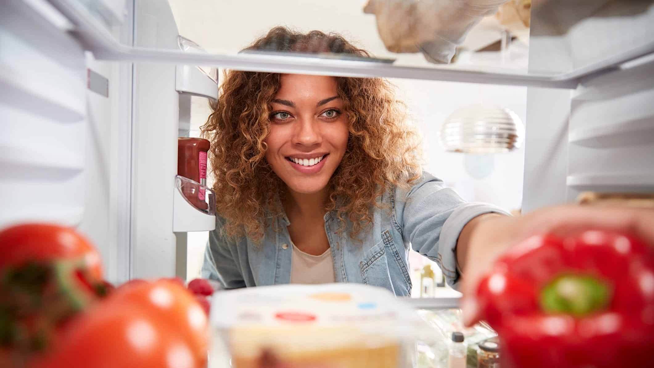 Une femme prend des aliments dans un frigo