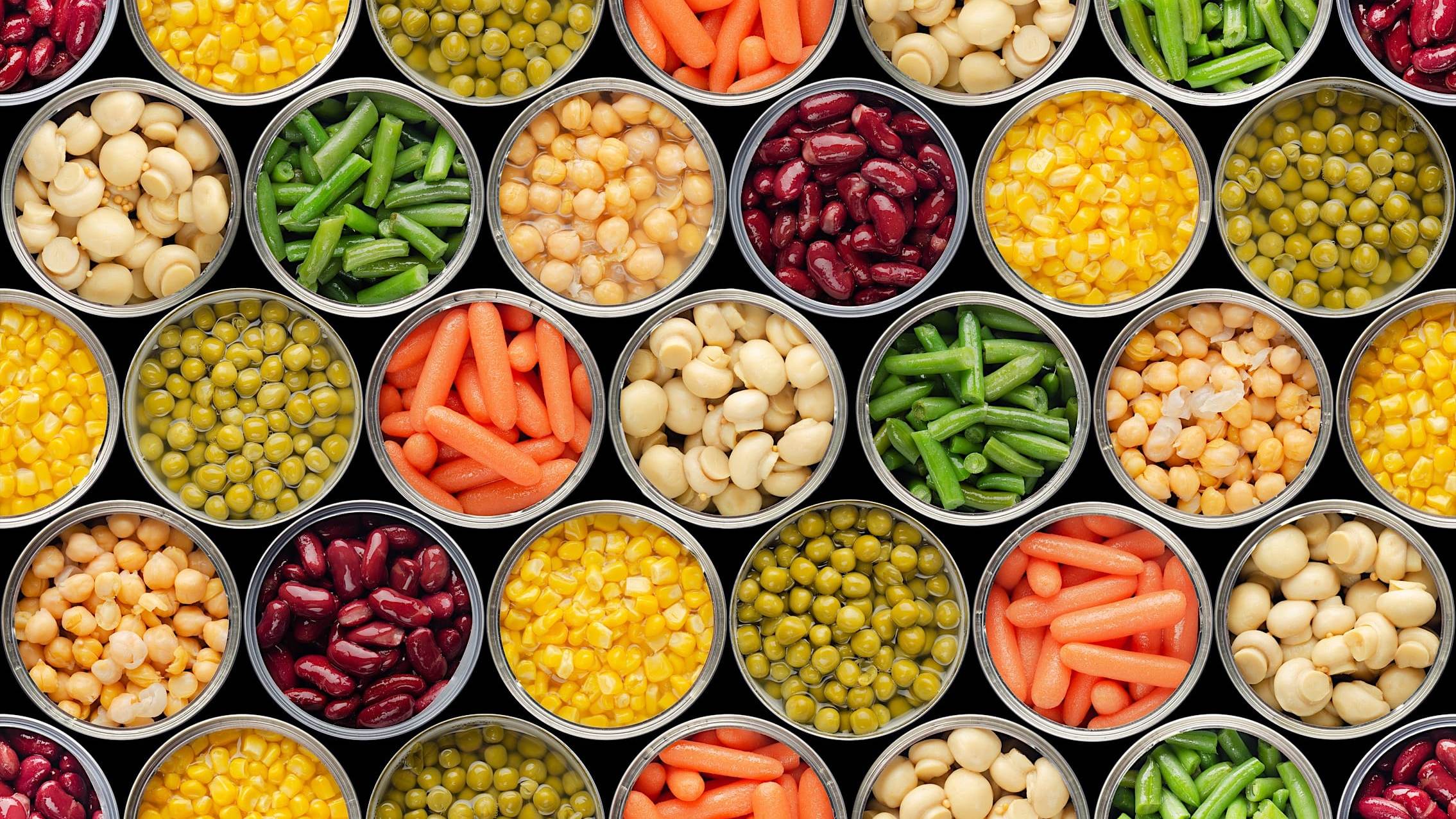 Gros plan sur des rangées de conserves ouvertes d'aliments variés: haricots verts, carottes, maïs, haricots rouges, petits pois, champignons et pois chiches