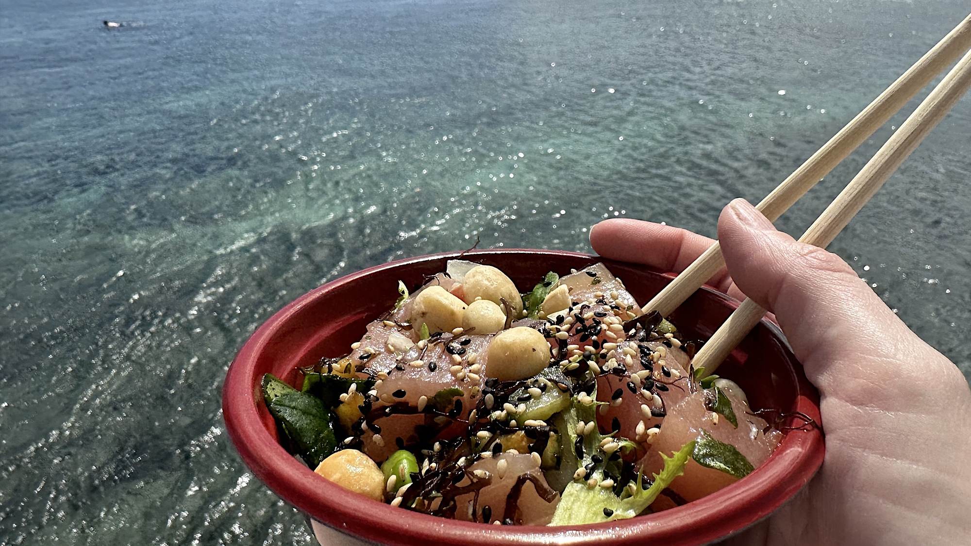Un bol de la recette originale de poke Hawaiien avec l'océan en fond de trame