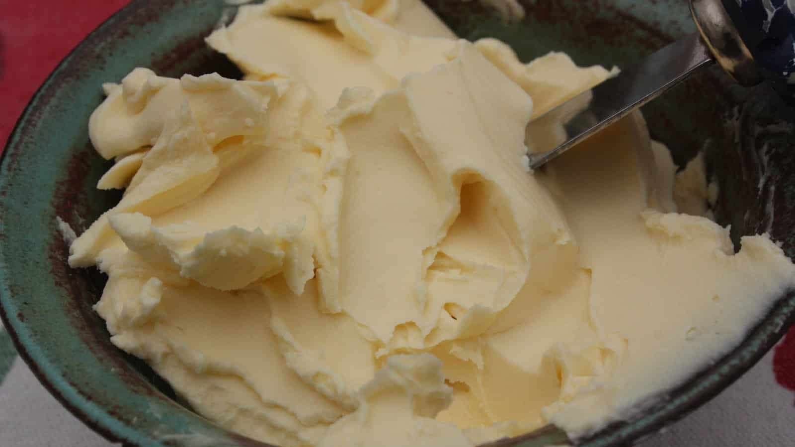 Du beurre en pommade dans un bol, un couteau à tartiner plongé dans le beurre