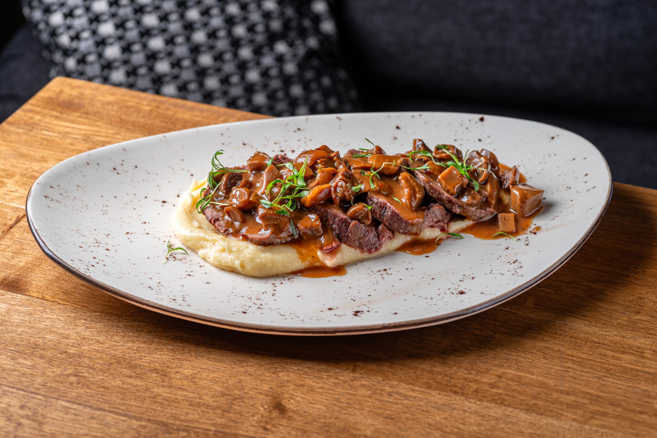 recettes-erable-boeuf un steak de boeuf tranché est posé sur une purée de pommes de terre et nappé de sauce au bourbon, érable et champignons