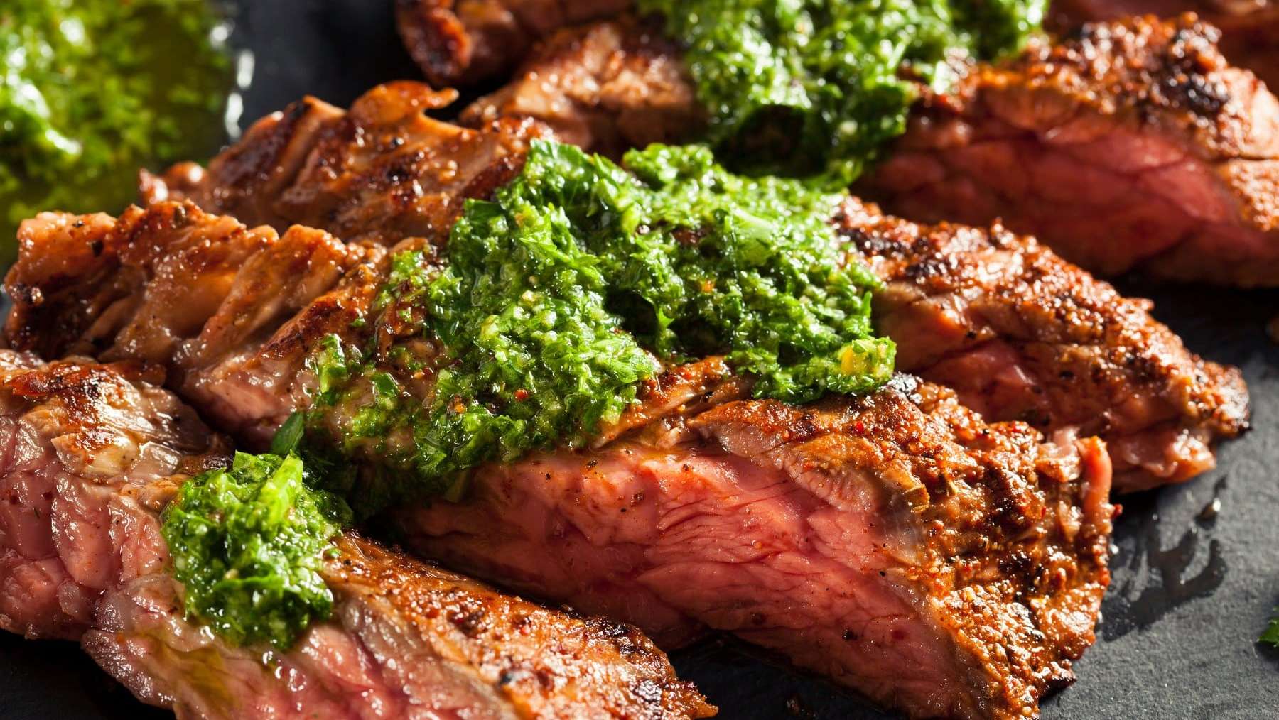 Des tranches de bavette de boeuf grillée au BBQ garnies de sauce verte chimichuri