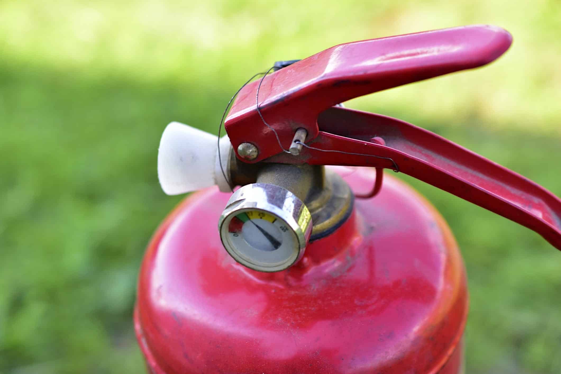 Erreurs-eviter-BBQ-extincteur Un extincteur de feu rouge sur un fond de gazon