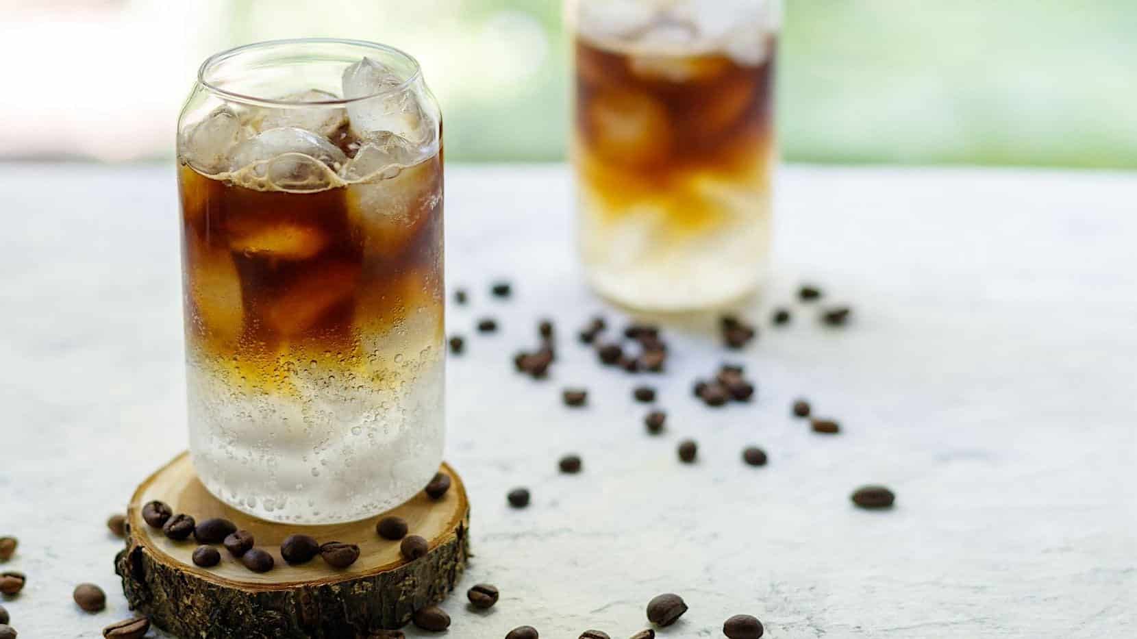 Deux verre contenant un mocktail espresso tonique pétillant et rafraichissant sont posés sur une table à l'extérieur.