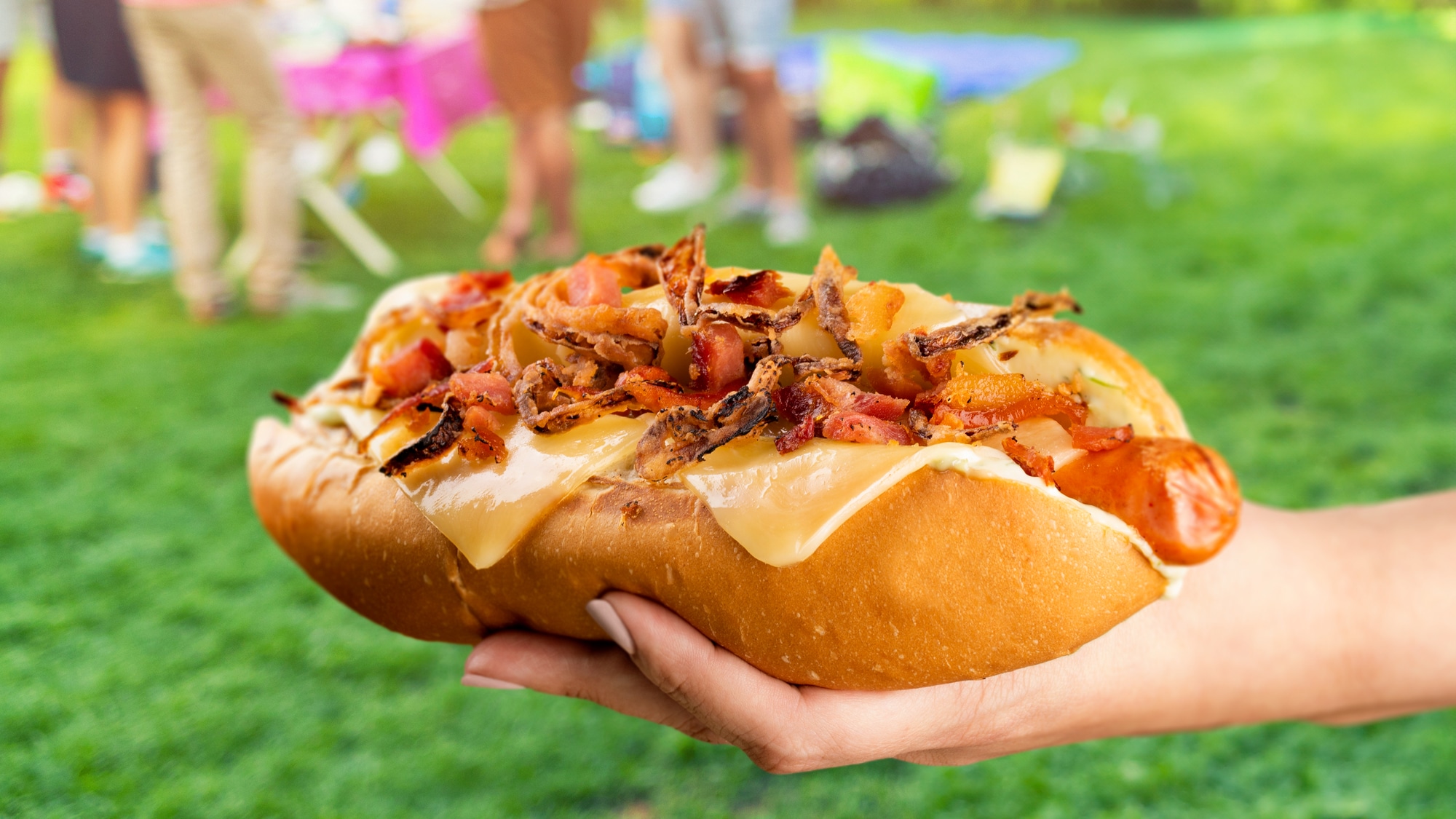 Une main de femme tient un hot-dog gourmet avec les saucisses l'épicier
