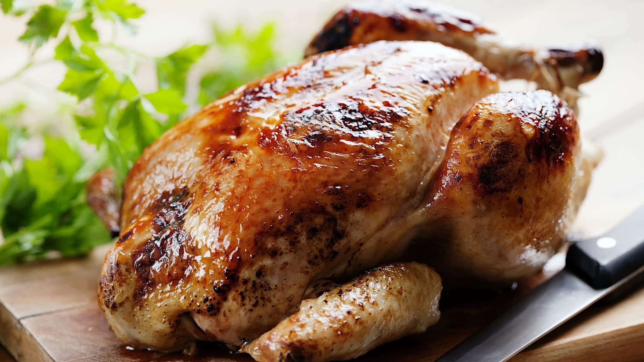 Un poulet rôti sur une canette de bière sur une planche à découper en bois