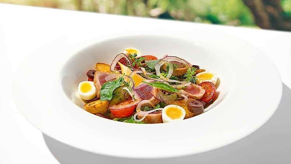 Une salade niçoise créé avec des ingrédients cuisinés au BBQ, servie avec des tranches de thon Yellowfin grillées