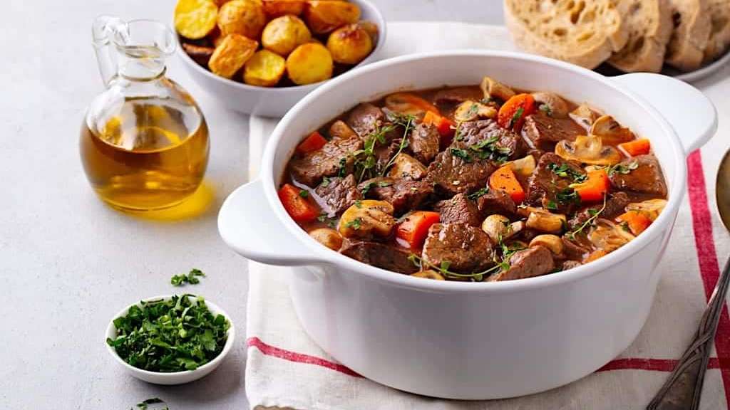 Un braisé de boeuf Bourguignon aux pommes est dressé dans une cocotte blanche