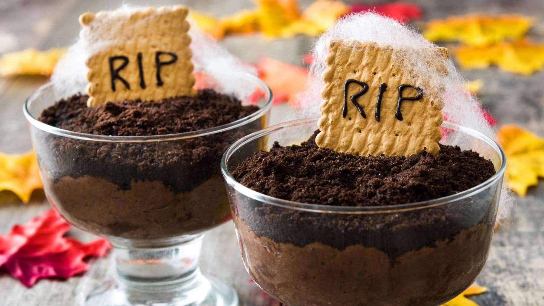 Deux verrines de mousse au chocolat garnies de biscuits émiéttés et d'un biscuit pierre tombale avec RIP d'écrit dessus, selon une recette pour l'Halloween