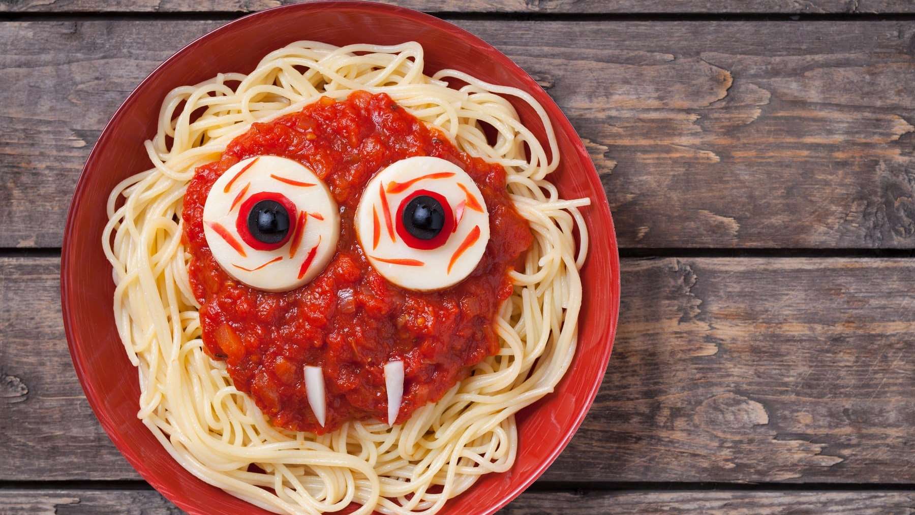 Une assiette de spaghetti garnis de sauce tomate avec un visage de vampire créé avec des ingrédients d'une recette pour l'Halloween