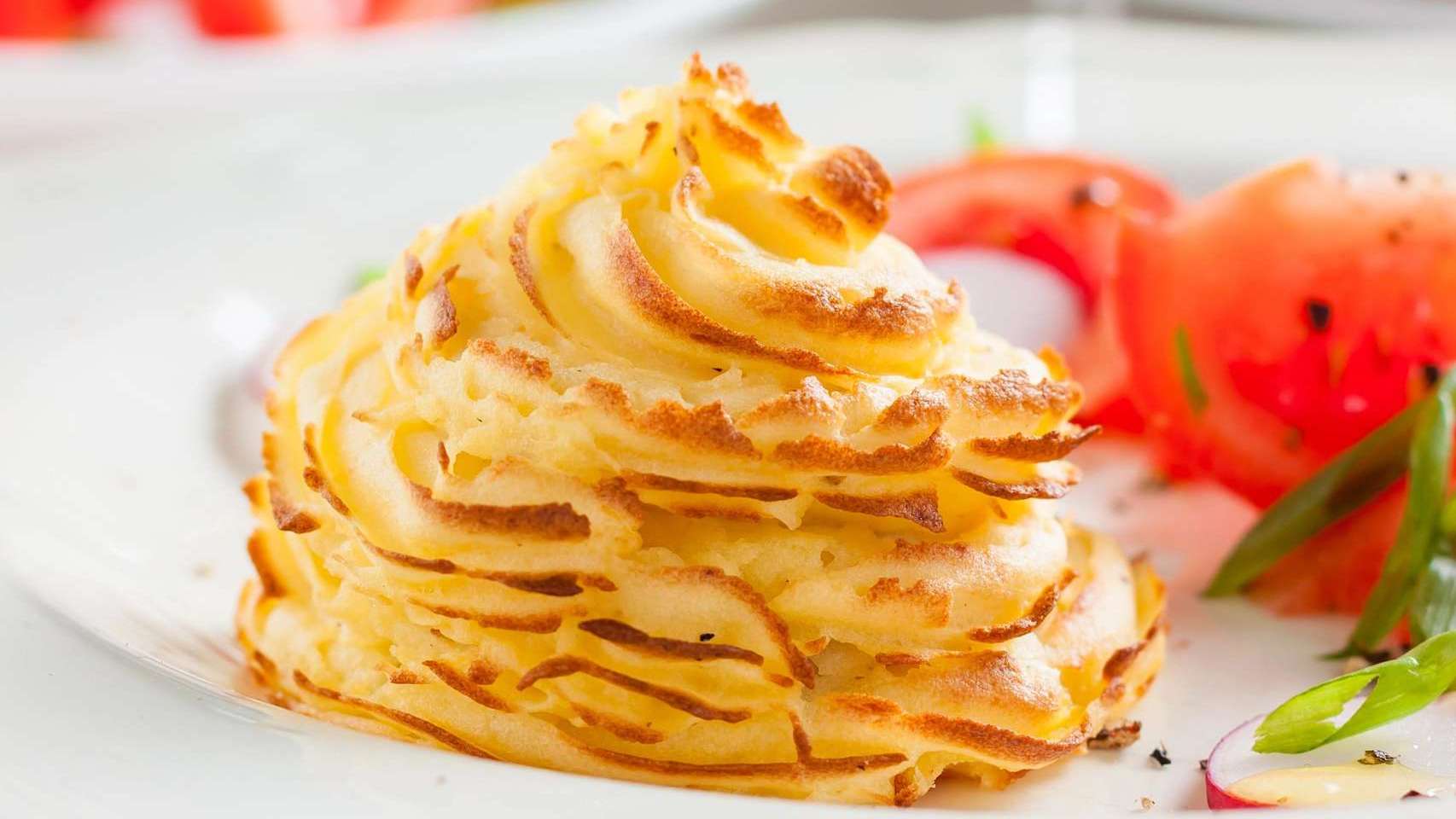 Une portion de pommes de terre dans une assiette blanche. Photo de recette de patates duchesse.