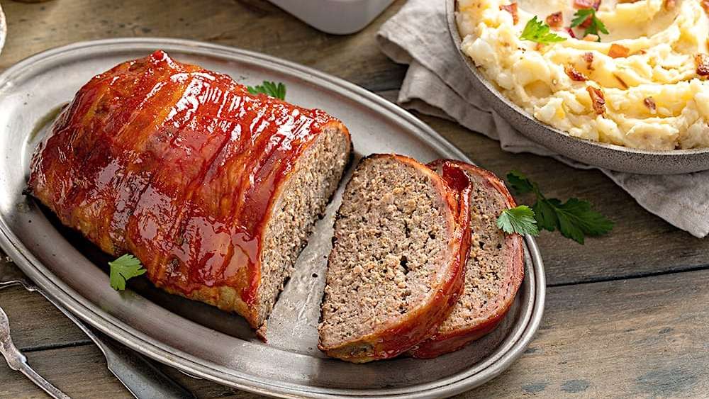 Un pain de viande est posée dans une assiette en aluminium, et un bol de pommes de terre purée l'accompagne