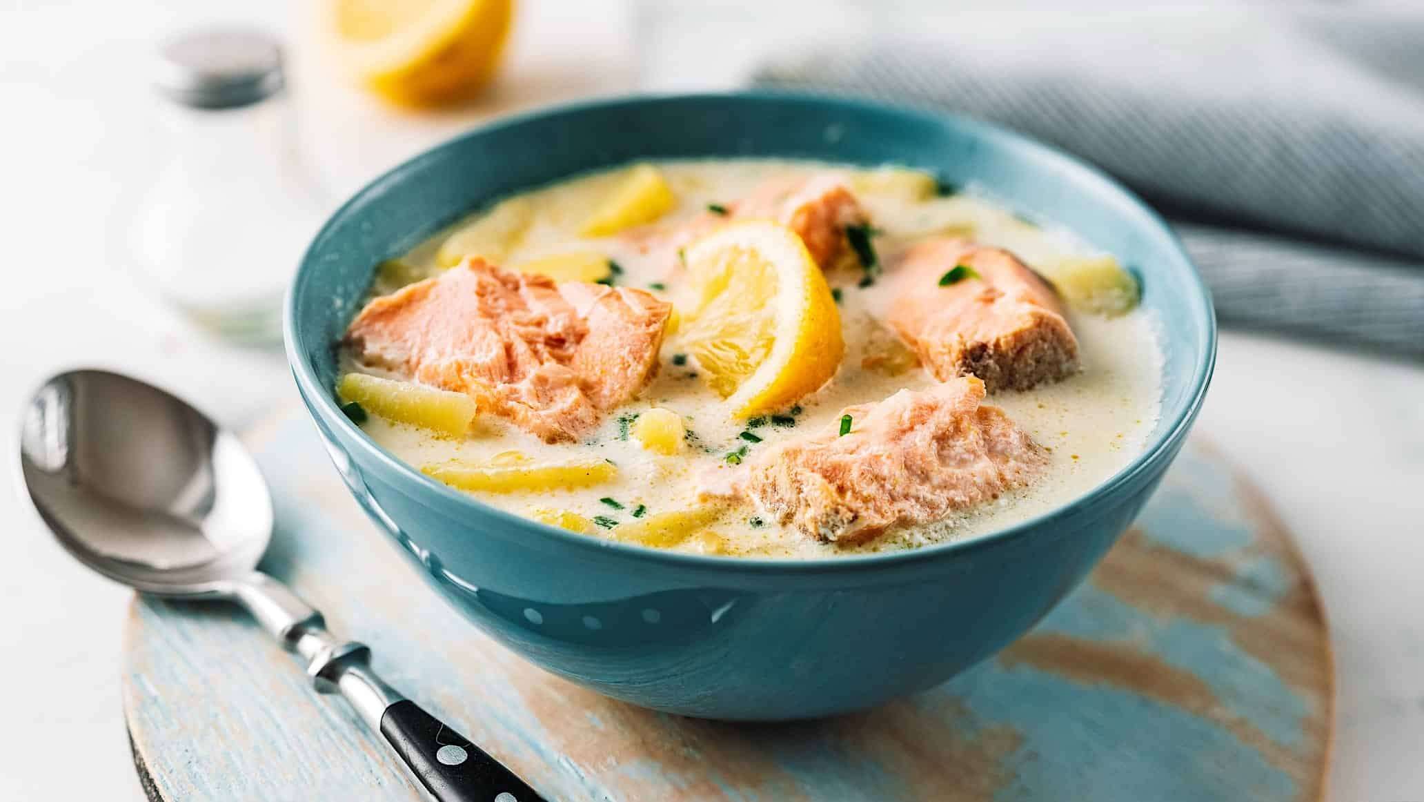 Une recette de chaudrée de saumon dans un bol à soupe bleu, accompagné d'une cuillère