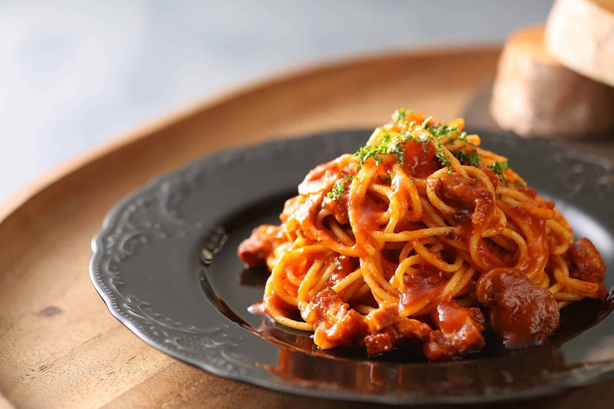 recettes-pates-sauce-tomate-beurre Une assiette noire garnie de pâtes italiennes avec une recette de sauce tomate au beurre.