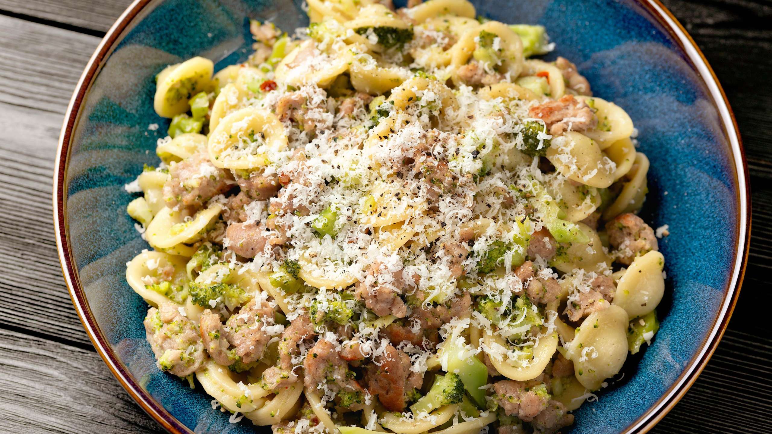 Une assiette-bol de pâtes italiennes avec une recette d'orrecchiette à la saucisse et aux rapinis