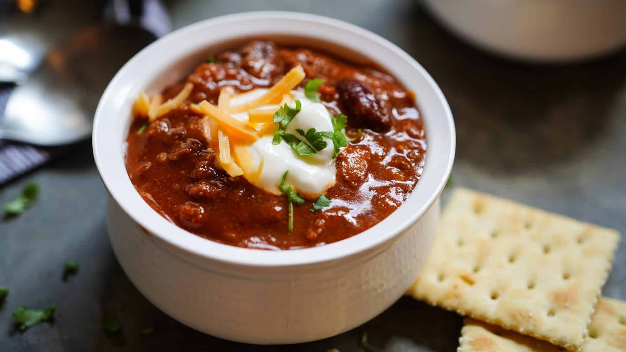 Un petit bol de chili con carne, une recette classique du Texas, garni de crème sure, de coriandre et de fromage râpé