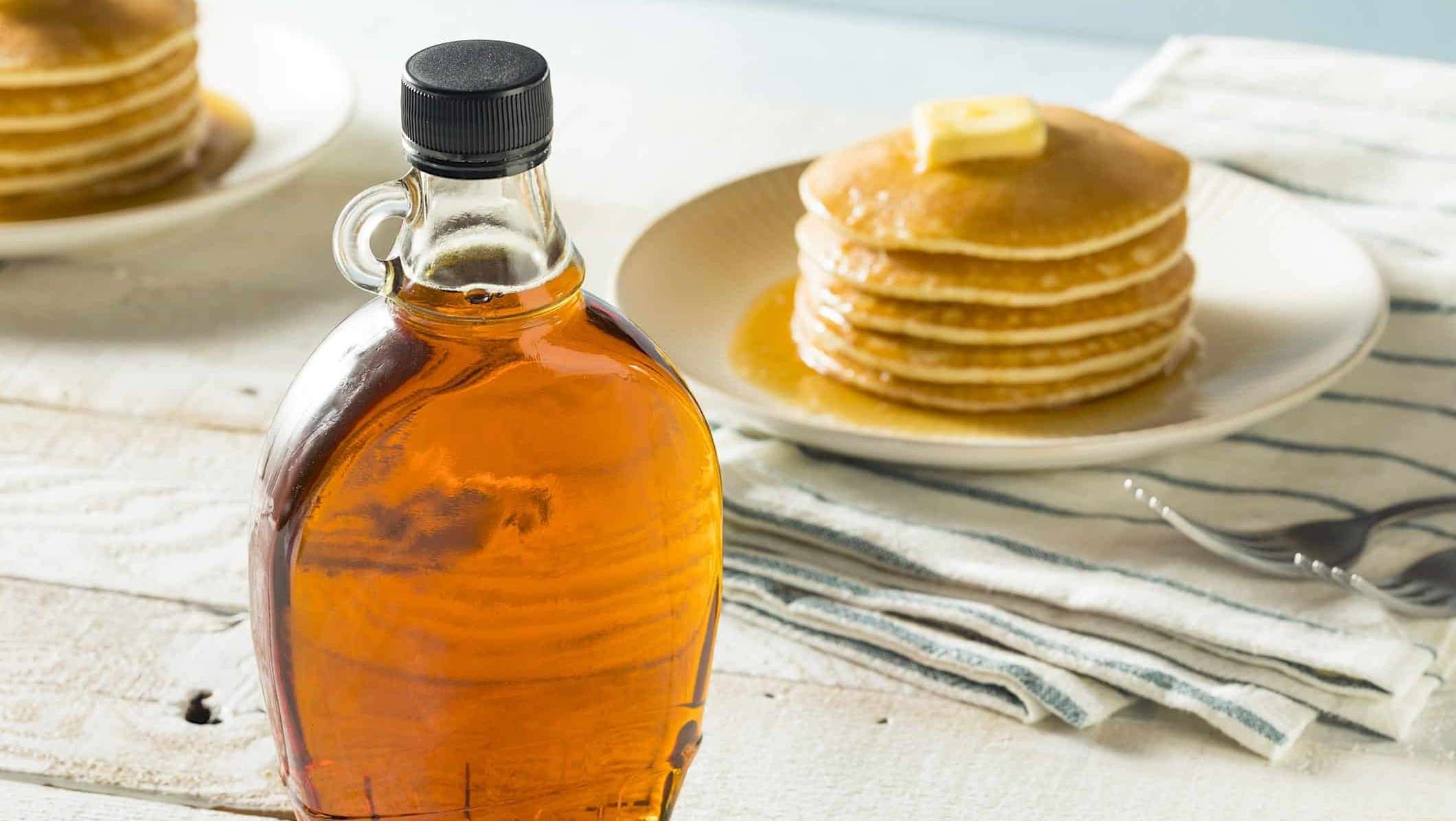 Une bouteille de sirop d'érable poséee sur une table en bois pour un menu de la cabane au sucre