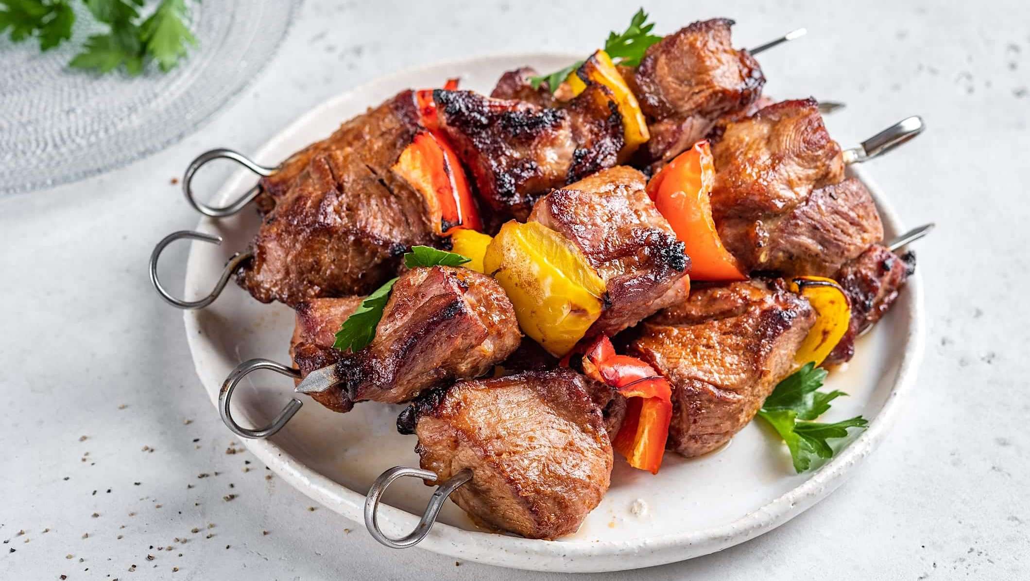 Une assiette de cubes de porc l'épicier montés en brochettes avec des légumes et cuites sur le BBQ