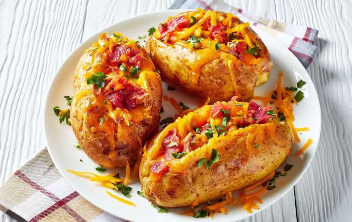 Une recette de pommes de terre grillées au BBQ et farcies, dressées sur une assiette blanche.