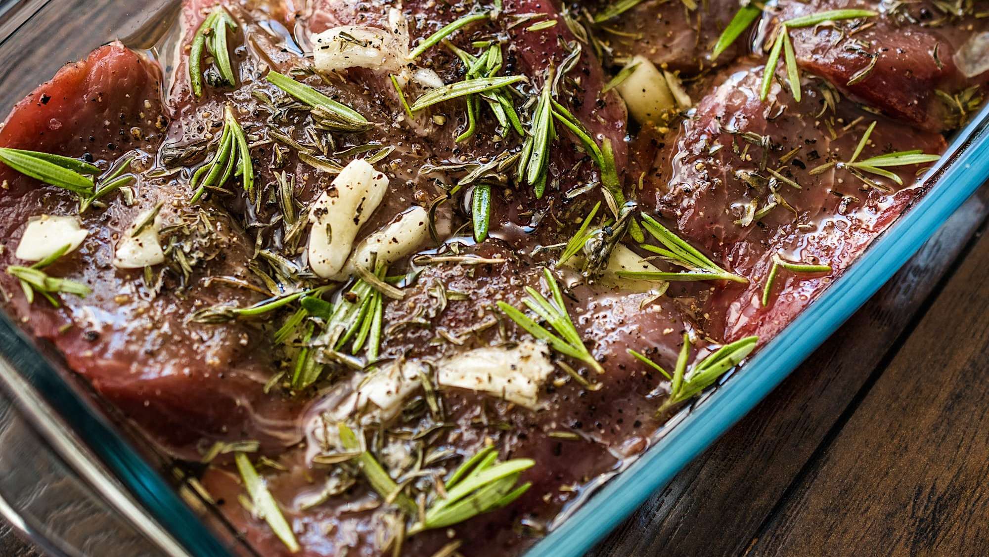 Des steaks de boeuf en marinade avec de l'ail, des épices et du romarin, destinés à être grillés sur le BBQ