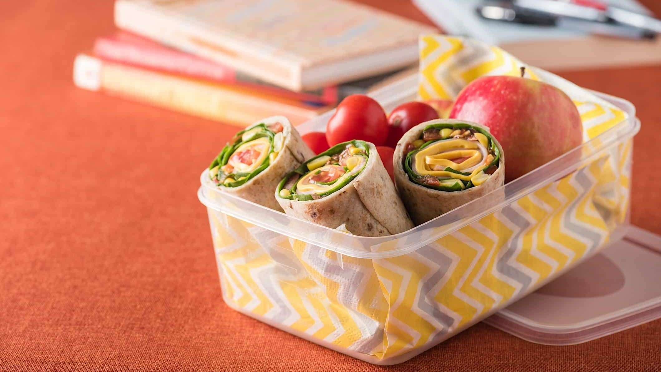 Lunch-adolescent-Wrap Un contenant en plastique rectangulaire contient un wrap protéiné pour une boîte à lunch pour adolescent nutritive et équilibrée