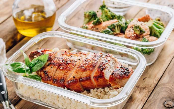 Une poitrine de poulet grillée au BBQ accompagnée de riz et de légumes sont posés dans une contenant de plastique pour préparer d'avance des lunchs pour la rentrée scolaire