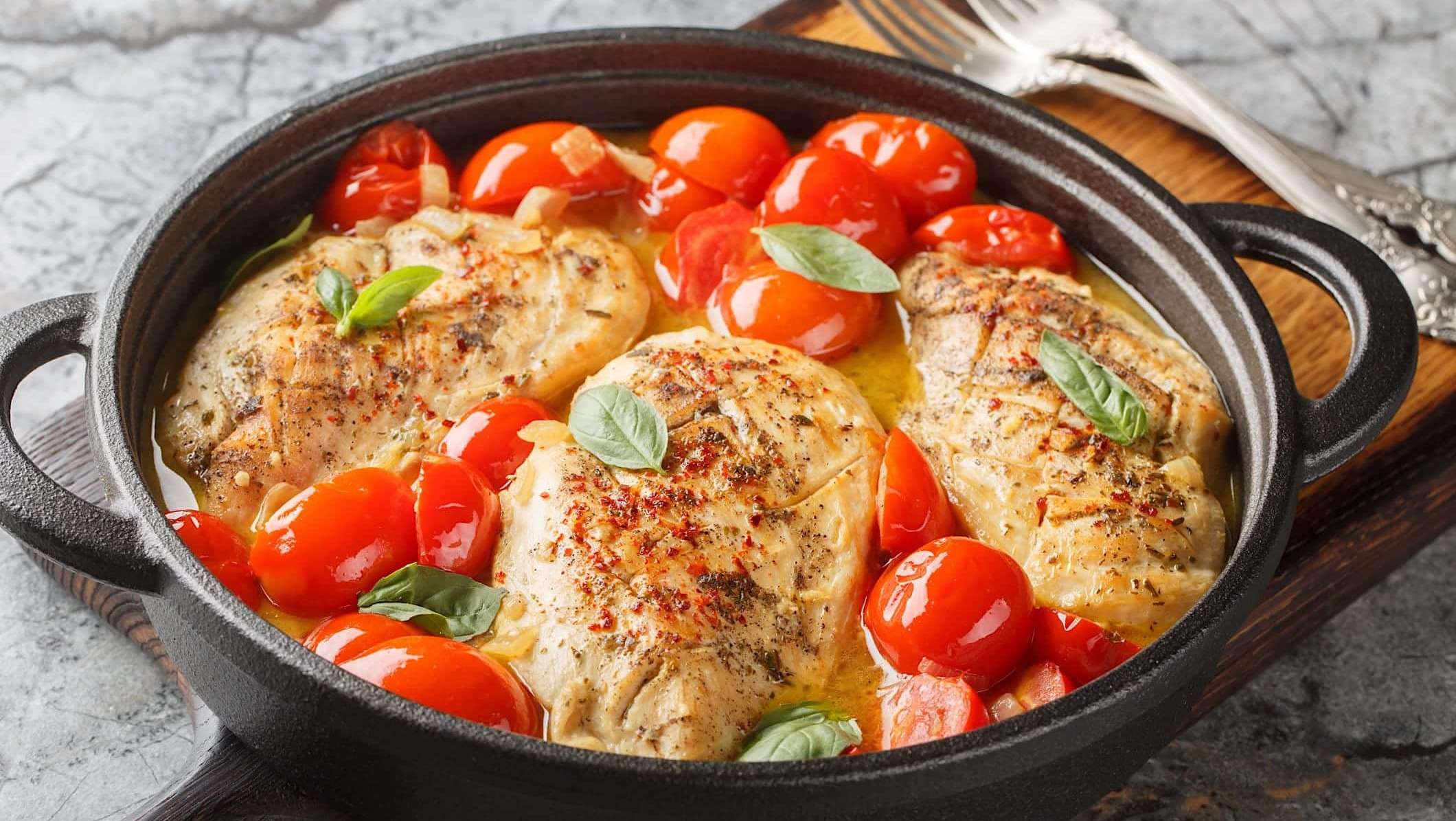Des poitrines de poulet et des tomates à l'italienne et garnies de basilic sont cuites dans une seule casserole pour un repas vite fait tout-en-un