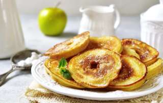 Beignets de pommes faciles cuisinés au airfryer sont posés sur une assiette blanche.