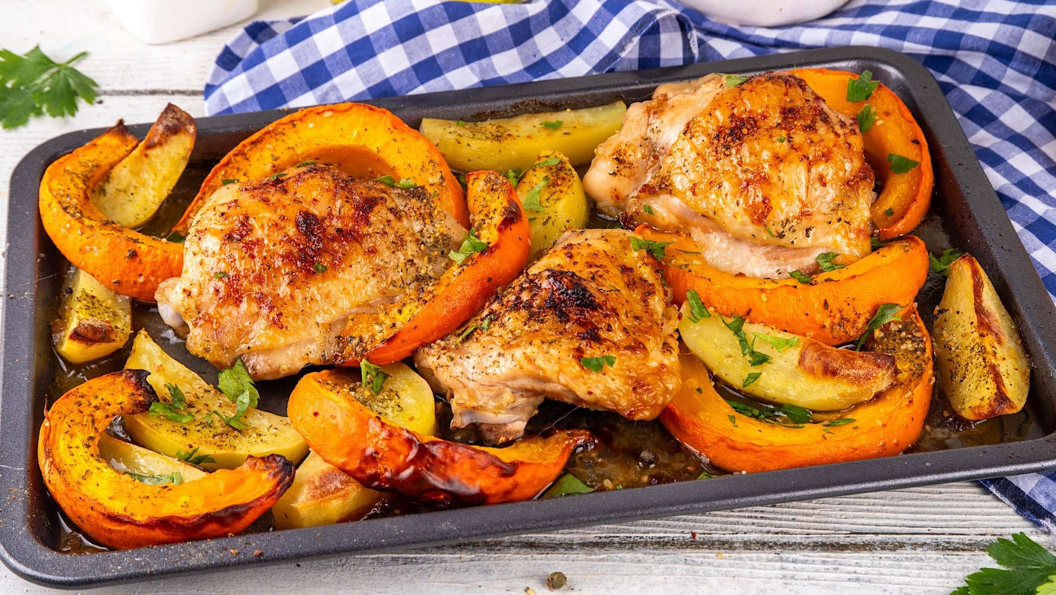 recettes-viande-citrouille_top Une plaque de cuisson au four est remplie de cuisses de poulet rôties au four avec des tranches de citrouilles et des quartiers de pommes de terre