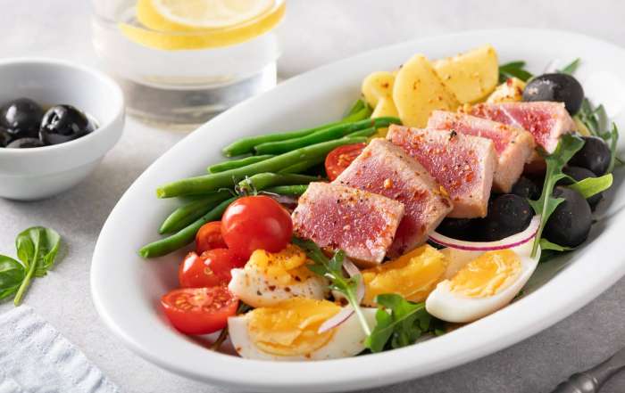 Une salade niçoise d'hiver protéinées avec du thon Yellowfin l'épicier, des oeufs, des légumes frais, surgelés et en conserve et des olives noires