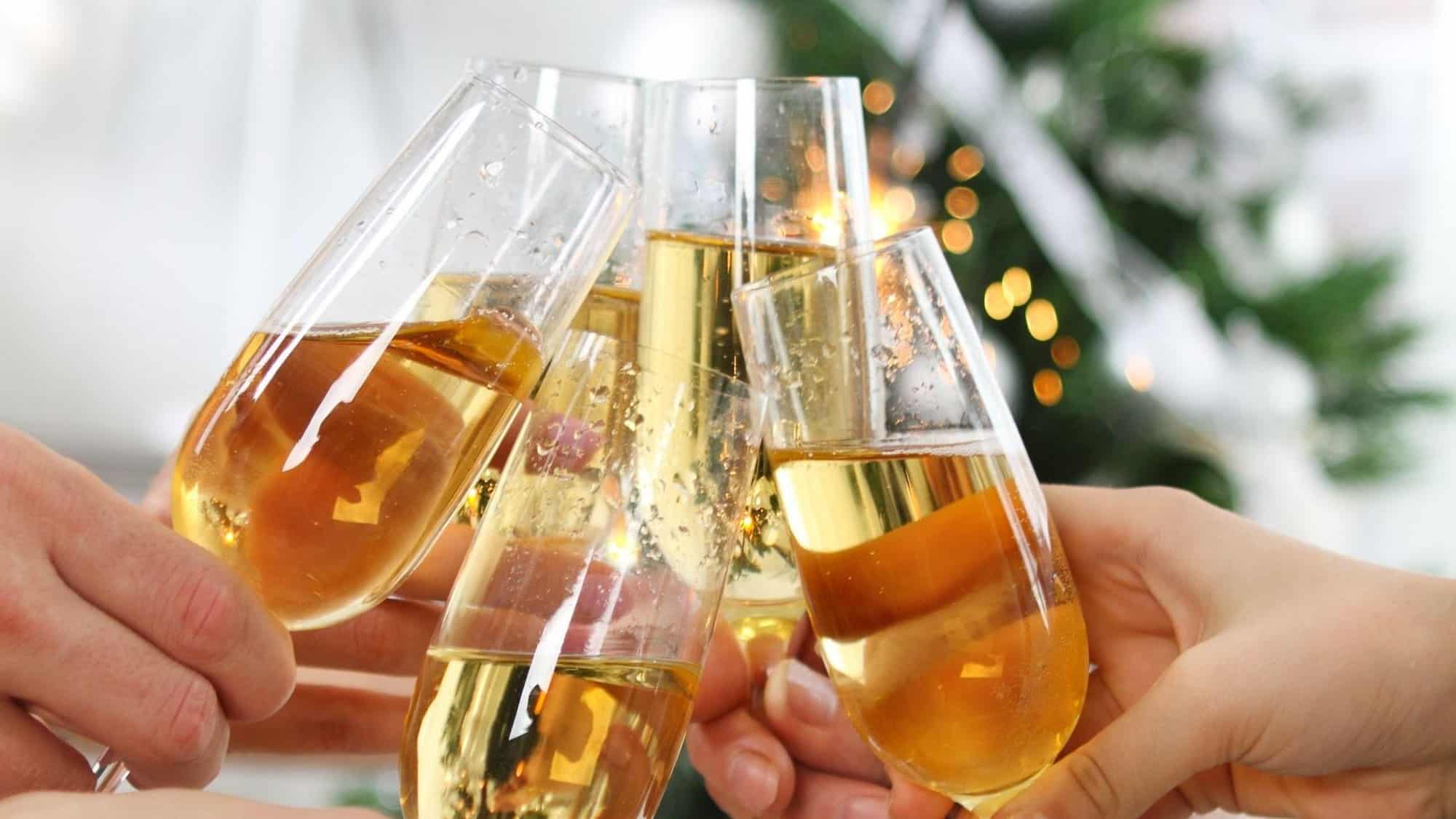 Des personnes font un toast commun en rassemblant des flûtes à champagne pour illustrer des cocktails à base de bulles pour le Nouvel An