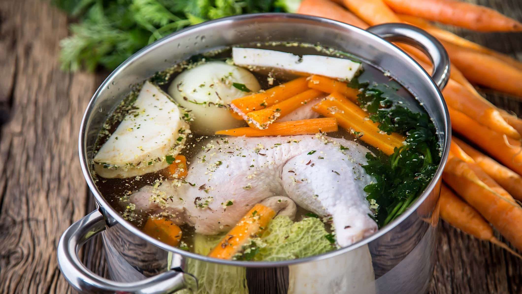 manger-boire-grippe-rhume-bouillon Une casserole remplie d'aliments pour faire un bouillon de poulet pour illustrer quoi manger et boire pour se soigner d'un rhume ou d'une grippe.