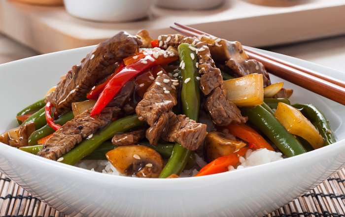 Un bol blanc contient une recette de sauté de boeuf et légumes pour des repas de semaines rapide