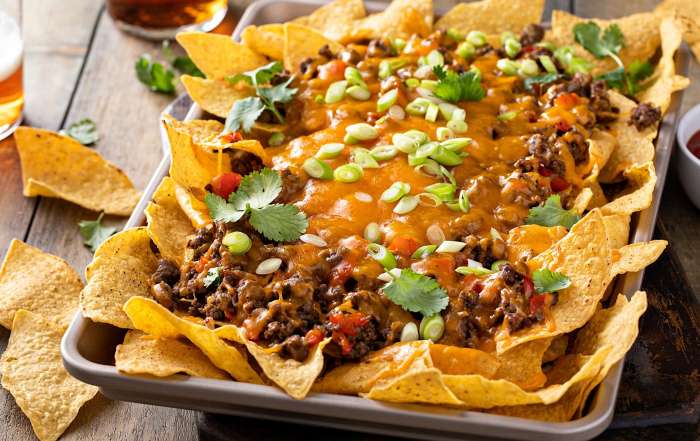 Une plaque de cuisson déborde de nachos garnis au boeuf haché, une recette simple à faire avec les enfants à la relâche scolaire.