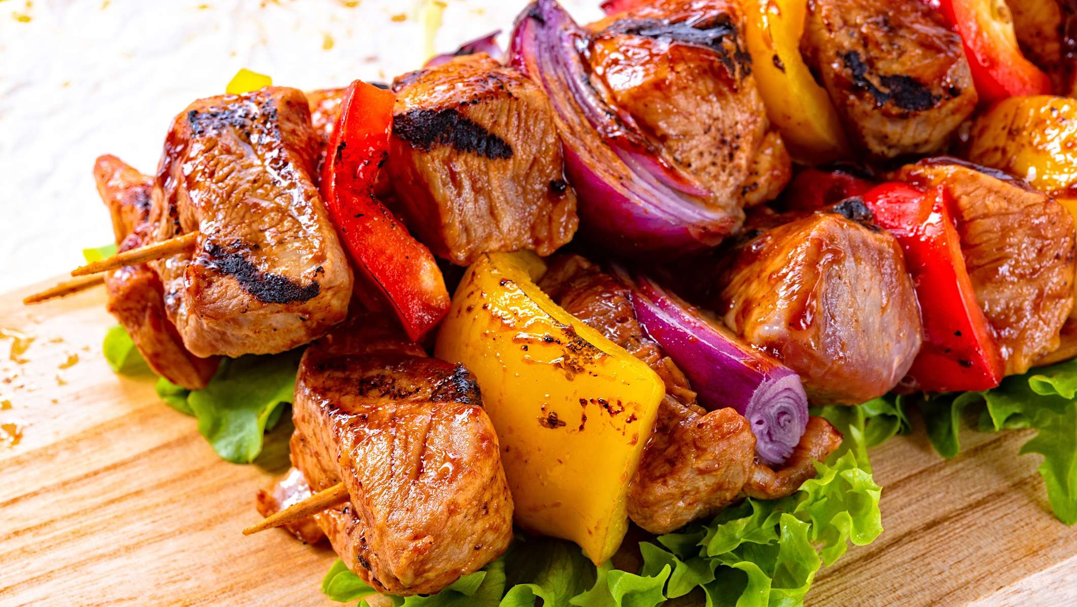 Deux brochettes du cubes de porc du Québec entrelacés de morceaux d'oignons rouge et de poivrons de couleurs, grillées au BBQ